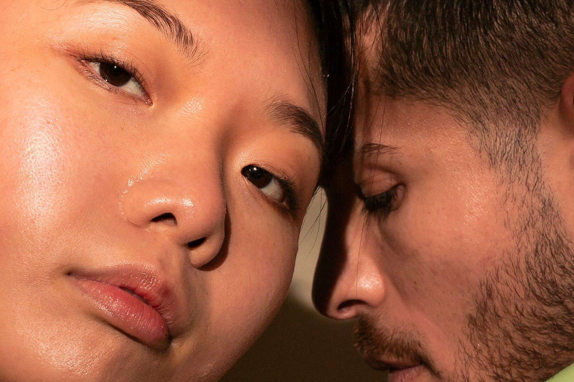 Two people holding skincare products against a neutral background