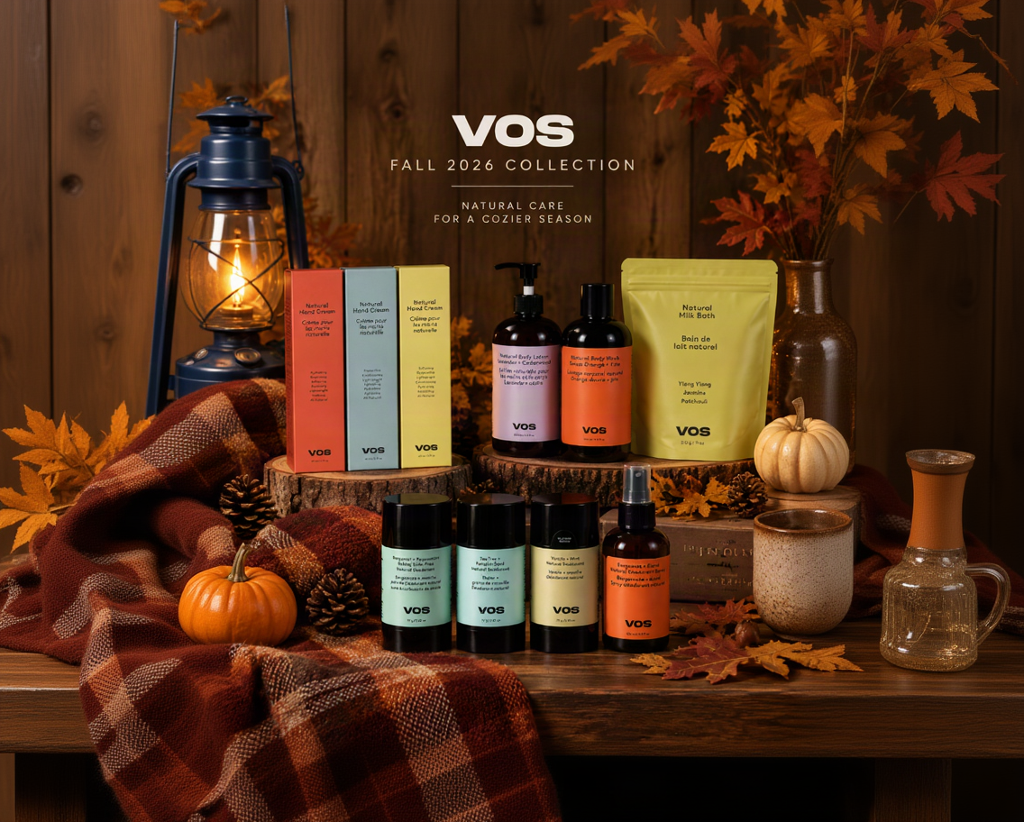 VOS Fall 2026 Collection skincare products arranged on a rustic wooden table with autumn props including fall leaves, a lantern, pumpkins, and a plaid blanket. Visible products include colorful boxes, pump bottles, and a pouch, with the VOS brand name prominently shown.